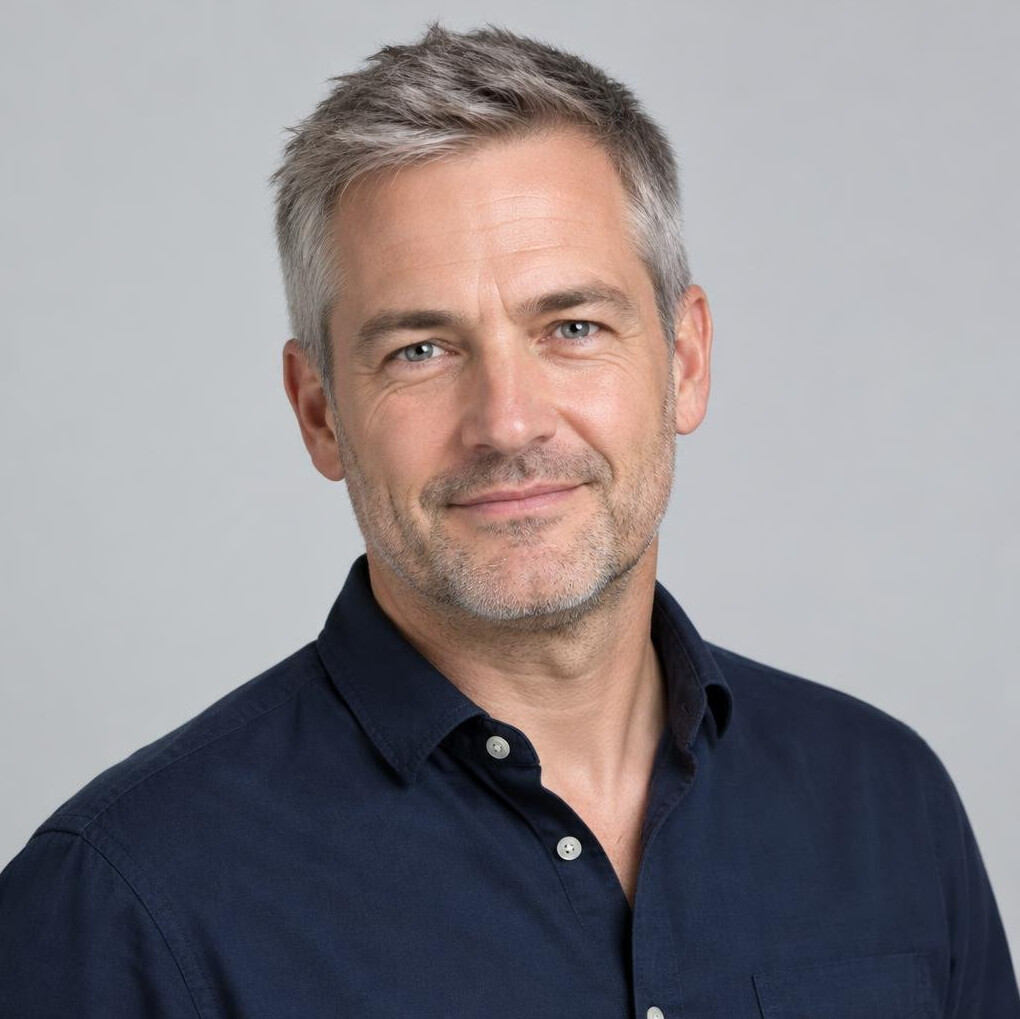 Portrait of a British man in his forties with short grey hair in a dark shirt